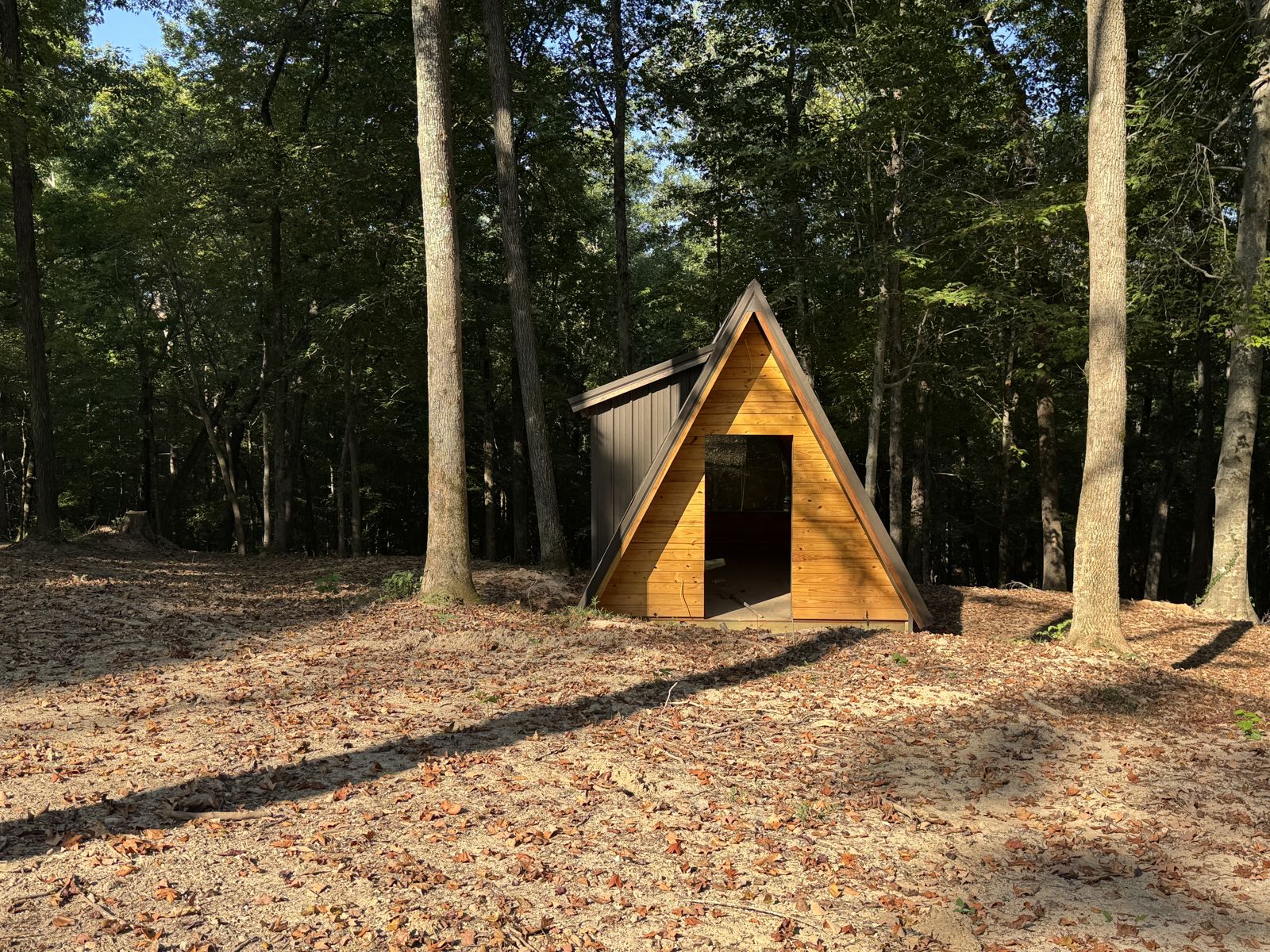 Front of an A-frame glamping cabin among the trees